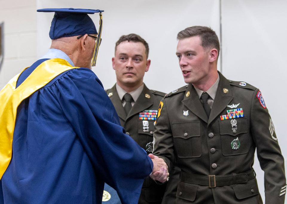 Jon Langione shakes the hands of two Army recruiters Staff Sergeants Brady Slack and Tyler Blumenstock before receiving his diploma on June 1. 
(Photo: Paul Kuehnel, York Daily Record)