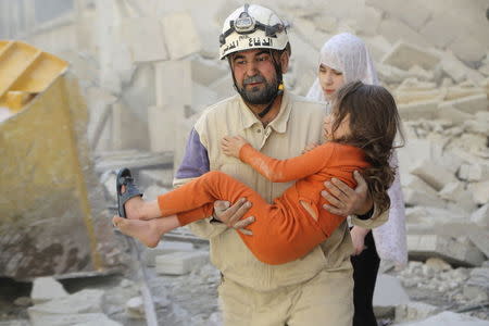 A civil defense member holds an injured girl in a site hit by what activists say was a barrel bomb dropped by forces loyal to Syria's President Bashar al-Assad, at Aleppo's Saif al-Dawla district May 7, 2015. REUTERS/Hosam Katan TEMPLATE OUT