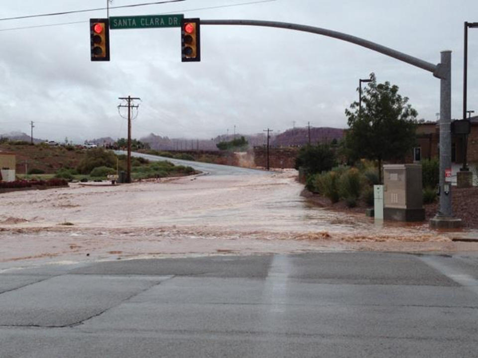 This photo released by the St. George Police Department shows a flooded street after a dike broke and sent floodwaters through the town of Santa Clara, Utah, Tuesday, Sept. 11, 2012. Officials in Santa Clara say they're inspecting whether people can return to about 60 homes and 15 businesses that were evacuated after a dike broke and sent floodwaters through town. City Parks and Recreation Director Brad Hays said a retention pond fed by the Tuacahn Wash filled up after heavy rains Tuesday morning. Authorities ordered homes and businesses below the pond to evacuate about noon, and the dike broke about 45 minutes later. No injuries have been reported from the flooding. (AP Photo/St. George Police Department)