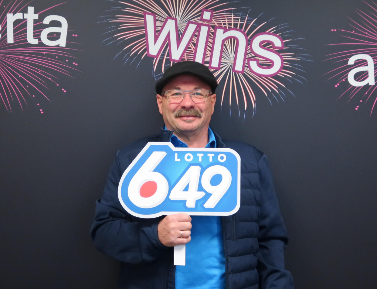 Man holds a Lotto 6/49 sign.