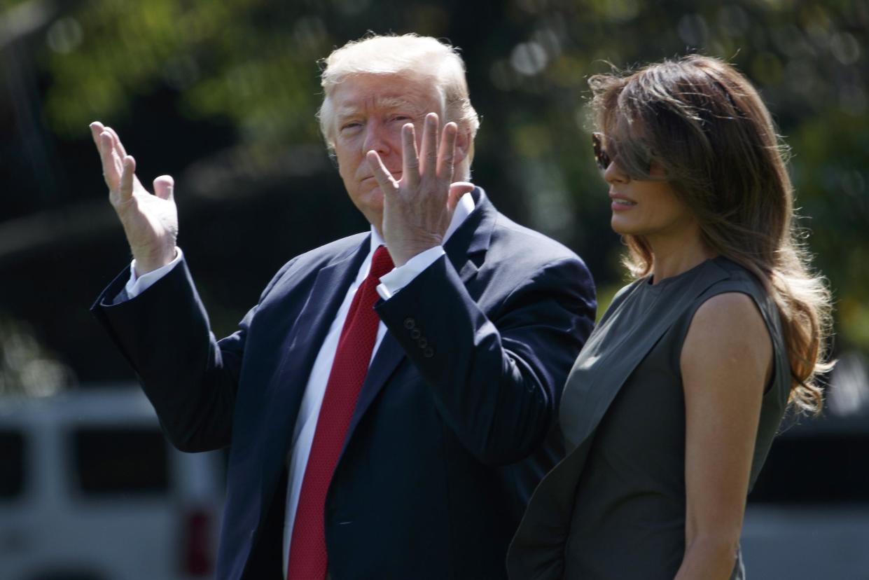 President Donald Trump gestures toward reporters as he walks with first lady Melania Trump to board Marine One: AP