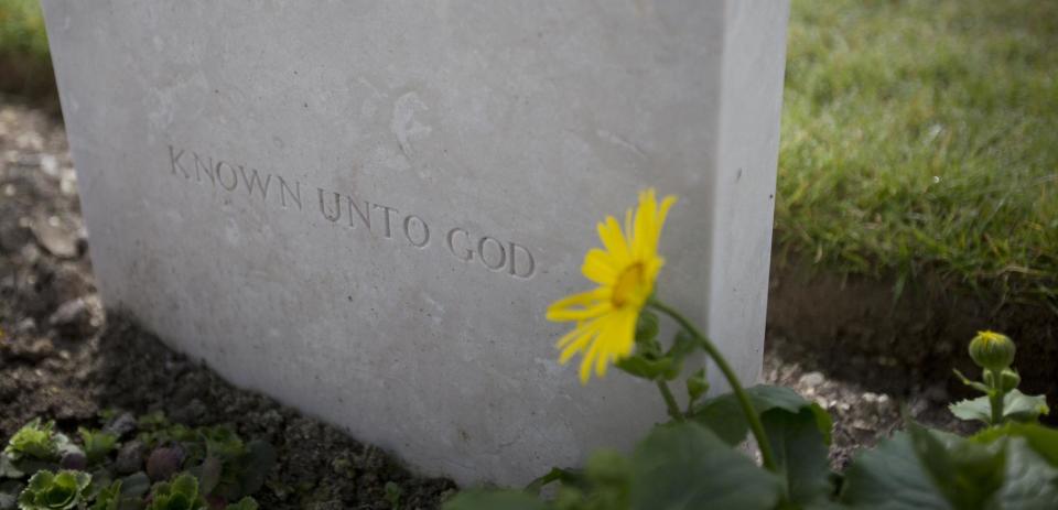 A flower grows next to the epitaph 'Known Unto God' on a gravestone for an unknown World War One soldier at Dud's Corner Cemetery in Loos-en-Gohelle, France on Thursday, March 13, 2014. Private William McAleer, of the 7th Battalion, Royal Scots Fusiliers, was killed in action on Sept. 26, 1915 during the Battle of Loos and his name has been on the wall of the missing at Dud's Corner for nearly 100 years. His body was found and identified in 2010, during routine construction in the area, and he will be reburied with full military honors, along with 19 unknown soldiers, at the Loos British Cemetery on Friday, March 14, 2014. (AP Photo/Virginia Mayo)