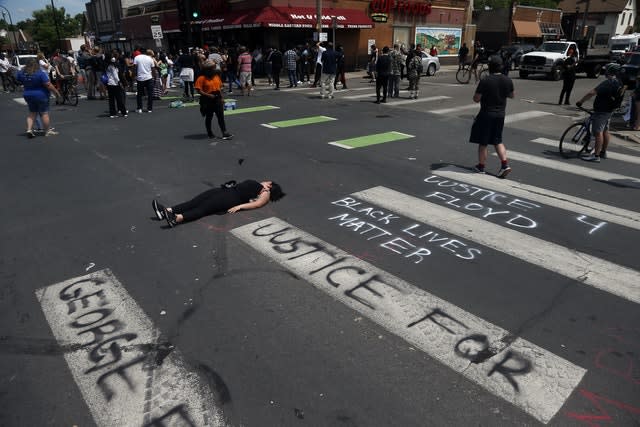 A woman lies in the street as protesters gather near the site of George Floyd's arrest 