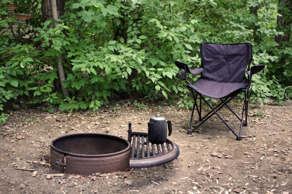 Camping chair next to empty, unlit fire pit