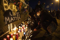 A woman lights a candle as people gather for Kevin Peterson Jr., who was killed in Thursday's shooting with police involved, at a candlelight vigil in Vancouver, Wash., Friday, Oct. 30, 2020. The Clark County Sheriff's office has not released any details on the Thursday evening shooting in Hazel Dell, but a man told The Oregonian/OregonLive that his 21-year-old son was fatally shot by police. (AP Photo/Paula Bronstein)