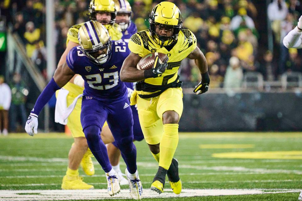 Oregon running back Noah Whittington (22) breaks away from Washington cornerback Mishael Powell (23) during their game in 2022 at Autzen Stadium.