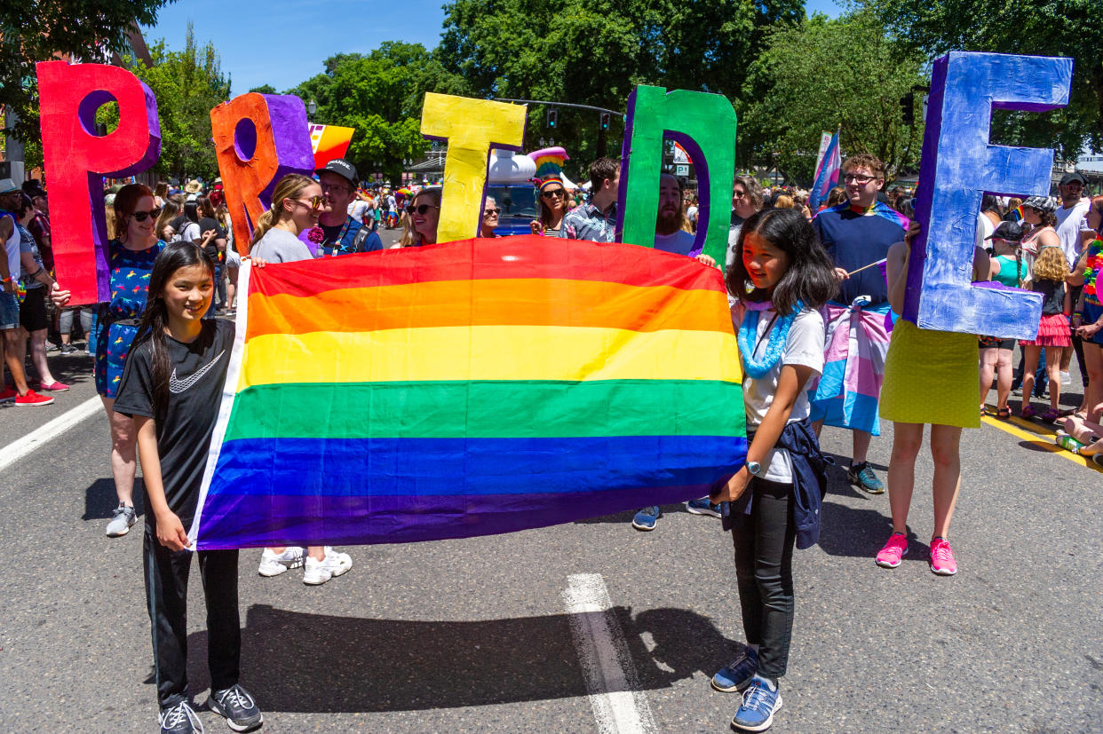 PORTLAND, OR - JUNE 16:  Two girls lead a segment of the parade with a rainbow flag followed by adults with the word 