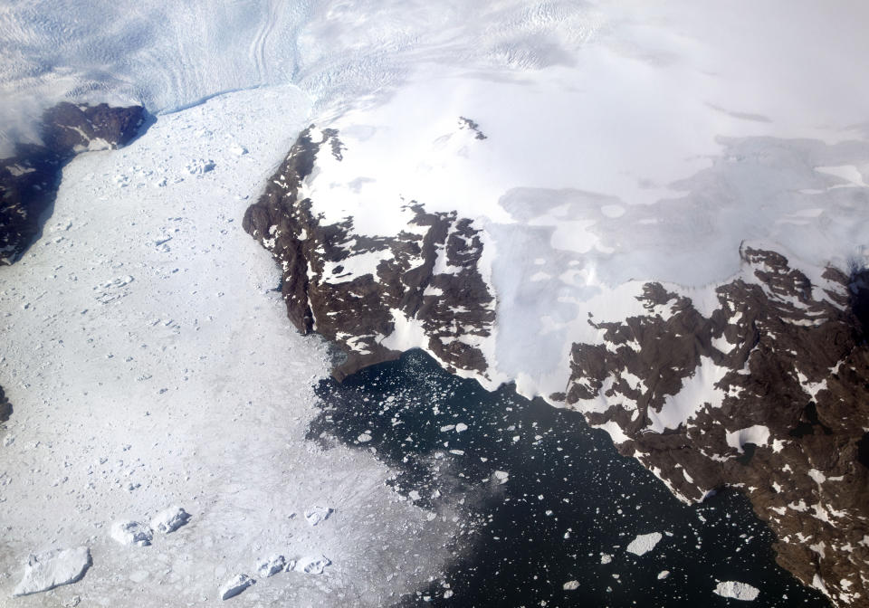 FILE - In this file photo dated Thursday, Aug. 3, 2017, a glacier at left calves icebergs into a fjord off the Greenland ice sheet in southeastern Greenland. The Danish Meteorological Institute said Sunday June 16, 2019, the melting season in Greenland has started a month earlier than usual, and issued a photo by climate researcher Rasmus Tonboe on Twitter showing what they say are sled dogs dragging a sleigh on the ice in Greenland with their paws in melted ice water.(AP Photo/David Goldman, FILE)