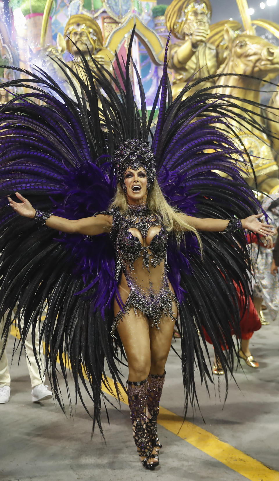 Transgender godmother Camila Prins from the Colorado do Bras samba school performs during a Carnival parade in Sao Paulo, Brazil, Sunday, Feb. 23, 2020. Prins entered the parade grounds, in a costume of feathers that displayed her sinuous body, fulfilling a dream nearly three decades old. (AP Photo/Andre Penner)