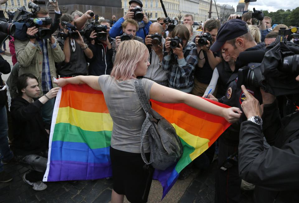 FILE - A gay rights activist stands with a rainbow flag, in front of journalists, during a protesting picket at Dvortsovaya (Palace) Square in St.Petersburg, Russia, Sunday, Aug. 2, 2015. Russia’s Supreme Court on Thursday, Nov. 30, 2023, effectively outlawed LGBTQ+ activism, in the most drastic step against advocates of gay, lesbian and transgender rights in the increasingly conservative country. (AP Photo, File)