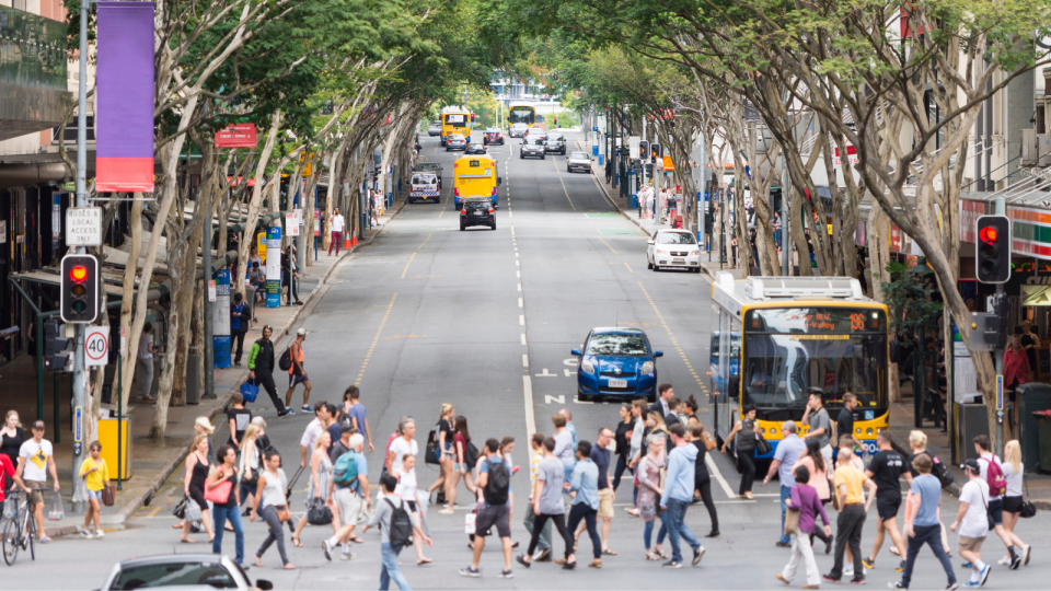 People and workers cross a busy street in Brisbane.