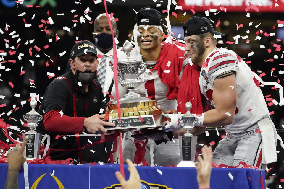 Ohio State head coach Ryan Day, from left, quarterback Justin Fields and linebacker Tuf Borland hold up the trophy after the team's win against Clemson in the Sugar Bowl NCAA college football game Friday, Jan. 1, 2021, in New Orleans. Ohio State won 49-28. (AP Photo/John Bazemore)