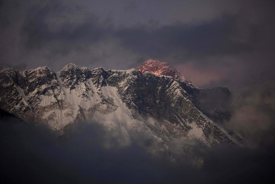 FILE - In this Oct. 27, 2011 file photo, the last light of the day sets on Mount Everest as it rises behind Mount Nuptse as seen from Tengboche, in the Himalaya's Khumbu region, Nepal. Guy Cotter was so concerned about the safety of Sherpa guides and porters through Mount Everest’s notorious Khumbu Icefall that he and another commercial guide operator hatched a plan: Before this year’s climbing season began, they would use helicopters to transport four tons of equipment above the icefall. Nepal-based Simrik Air backed the plan and hired New Zealand pilot Jason Laing, an expert in hauling loads using long cables. But in January, the answer came back from Nepalese authorities: permit denied. Three months later, Laing put his expertise to use. But not hauling gear. On April 18 came Everest’s worst disaster, in which 16 Sherpas were killed in an avalanche at the icefall. Laing made flight after flight that day, using his long cables to rescue four injured Sherpas and haul out 13 bodies. (AP Photo/Kevin Frayer, File)