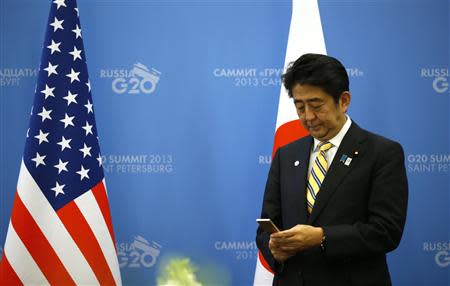 Japanese Prime Minister Shinzo Abe checks his phone while waiting for U.S. President Barack Obama (not seen) to arrive for their meeting at the G20 summit in St. Petersburg September 5, 2013. REUTERS/Kevin Lamarque