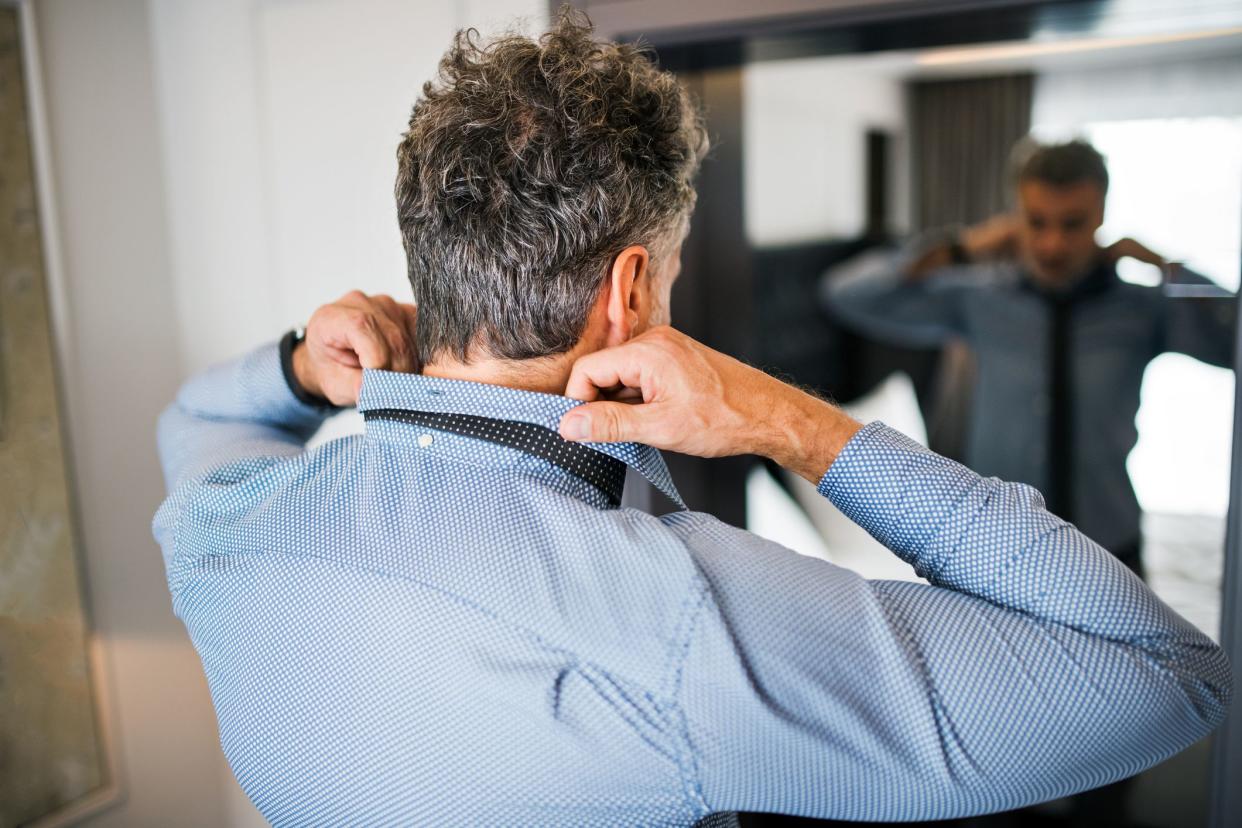 businessman putting on shirt and tie