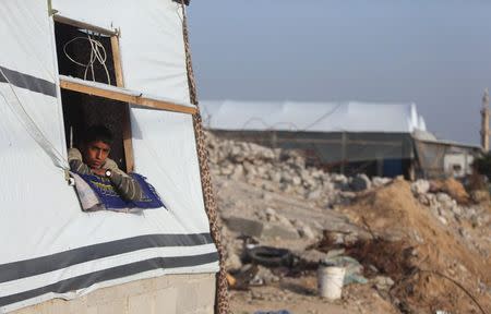 A Palestinian boy looks out a makeshift shelter near the rubble of his family's house, that witnesses said was destroyed by Israeli shelling during a 50-day war last summer, in Khan Younis in the southern Gaza Strip, March 10, 2015. REUTERS/Ibraheem Abu Mustafa