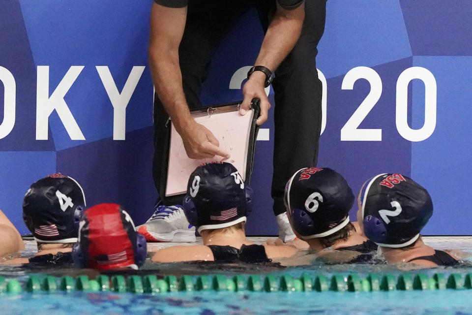 United States players listen to head coach Adam Krikorian during a timeout in a preliminary round women's water polo match against Hungary at the 2020 Summer Olympics, Wednesday, July 28, 2021, in Tokyo, Japan. (AP Photo/Mark Humphrey)