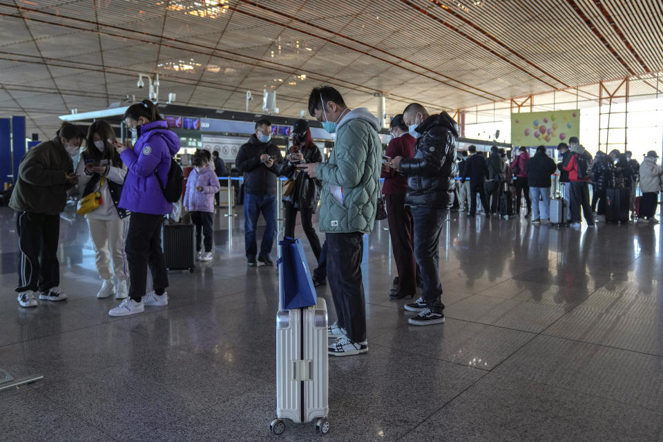 Masked travellers use their smartphones to fill in their health declaration after checking in at the international flight check in counter at the Beijing Capital International Airport in Beijing, Thursday, Dec. 29, 2022. Moves by the U.S., Japan and others to mandate COVID-19 tests for passengers arrsiving from China reflect global concern that new variants could emerge in its ongoing explosive outbreak — and the government may not inform the rest of the world quickly enough. (AP Photo/Andy Wong)