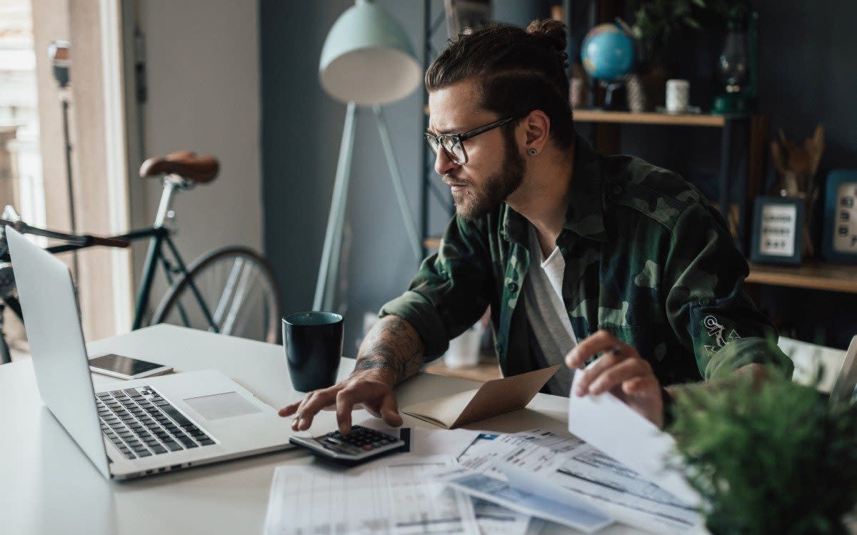 Young male freelance worker with his laptop and paperwork