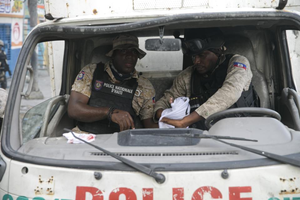 A wounded police officer, left, is helped by his mate to stop the bleeding from his hand after clashes during a protest to demand the resignation of Haiti's president Jovenel Moise on the 216th anniversary of Battle of Vertieres in Port-au-Prince, Haiti, Monday, Nov. 18, 2019. At least four people were shot and wounded during a small protest in Haiti’s capital after a speech by embattled President Jovenel Moise. A local journalist, a police officer and two protesters were rushed away with apparent bullet wounds. (AP Photo/Dieu Nalio Chery)