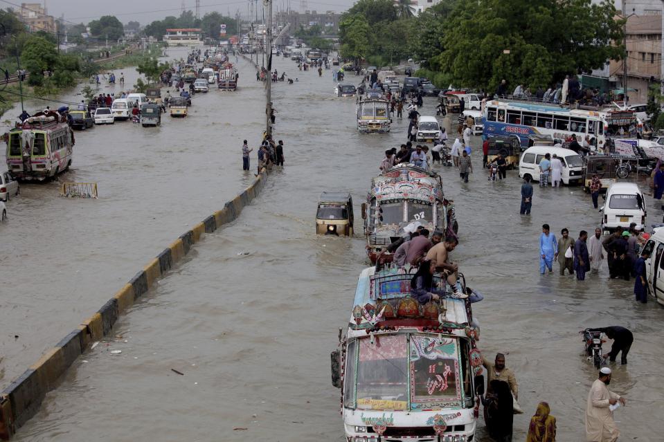 FILE - In this Aug. 27, 2020, file photo, vehicles drive through a flooded road after heavy monsoon rains, in Karachi, Pakistan. Heavy monsoon rains lashed many parts of Pakistan as well the southern port city of Karachi, leaving flooding streets, damaging homes and displacing scores of people. This year has seen record Atlantic hurricanes and western wildfires, devastating floods in Asia and Africa and a hot, melting Arctic. It's not just been a disastrous year, but a year of disasters. (AP Photo/Fareed Khan, File)