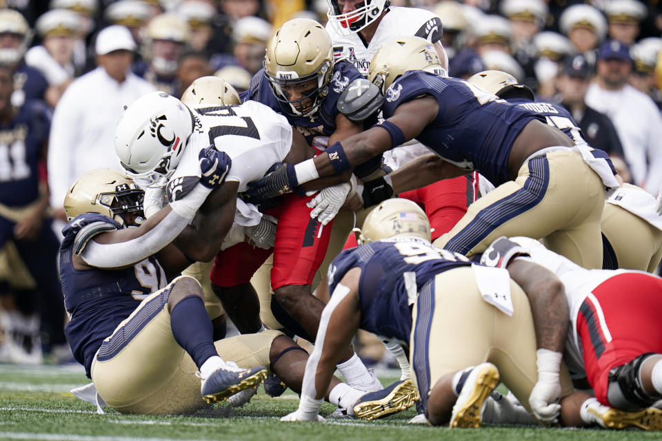 Cincinnati running back Jerome Ford (24) is tackled by a host of Navy defenders during the first half of an NCAA college football game, Saturday, Oct. 23, 2021, in Annapolis, Md. (AP Photo/Julio Cortez)