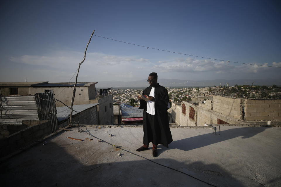 Entrepreneur and youth leader Pascéus Juvensky St. Fleur, who studied as a lawyer, reads from a copy of the Haitian constitution in the legal garb he often wears at anti-government protests, during an interview with the AP in his Delmas neighborhood of Port-au-Prince, Haiti, Tuesday, Oct. 8, 2019. St. Fleur says the protests are not only about replacing a president, but changing a system. "It's not one person, it's not one regime, it's not a president, it's not the opposition, it's not the bourgeoisie, but it's us who should do it," he said. "We dream of, and we want, a better Haiti."(AP Photo/Rebecca Blackwell)