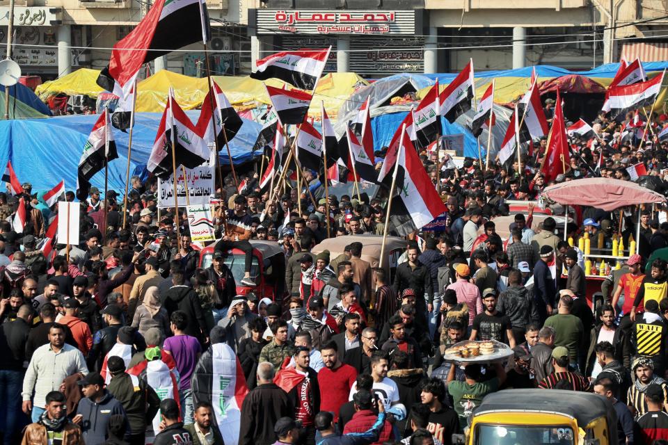 Hundreds of people march inside Tahrir Square carrying national flags and chanting religious slogans in Baghdad, Iraq, Thursday, Dec. 5, 2019. Anti-government protesters say multiple people have suffered stab wounds in Baghdad's Tahrir Square, the epicenter of their movement, after political parties and Iran-backed militia groups briefly joined them, raising fears of infiltration by authorities. (AP Photo/Hadi Mizban)