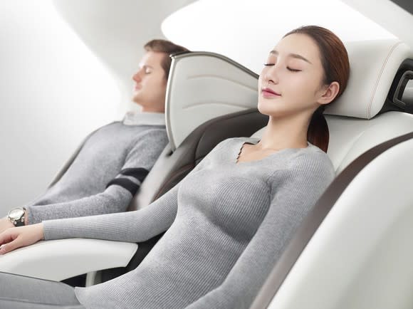 Two people with eyes closed leaning back in luxurious custom seats.