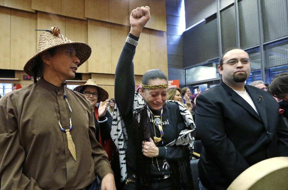 Olivia One Feather, center, of the Standing Rock Sioux tribe, holds her fist up and cries tears of happiness after the Seattle City Council voted to divest from Wells Fargo over its role as a lender to the Dakota Access pipeline project and other business practices, Tuesday, Feb. 7, 2017, in Seattle. Wells Fargo manages more than $3 billion of Seattle's operating account. (AP Photo/Elaine Thompson)