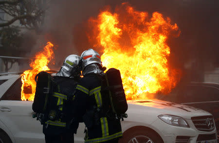 Firefighters try to extinguish a burning car during a demonstration of the "yellow vests" movement in Nantes, France, January 12, 2019. REUTERS/Stephane Mahe