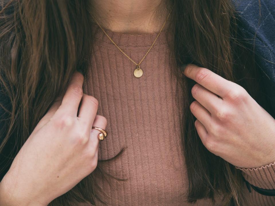 woman wearing a simple gold necklace with a winter outfit