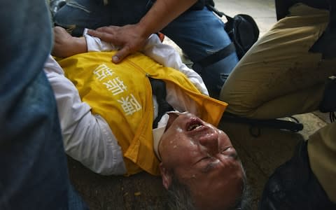 Chan, a candidate for district council elections, lies on the floor after being pepper-sprayed - Credit: MIGUEL CANDELA/EPA