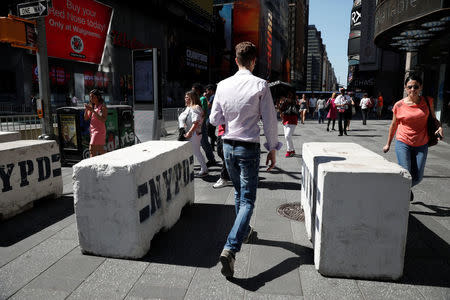 People walk between newly erected concrete barricades outside the 3 Times Square building in Times Square where a speeding vehicle struck pedestrians Thursday in New York City, U.S., May 19, 2017. REUTERS/Mike Segar