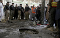 Police officers examine the site of bomb explosion in an Islamic seminary in Peshawar, Pakistan, Tuesday, Oct. 27, 2020. A powerful bomb blast ripped through an Islamic seminary on the outskirts of the northwest Pakistani city of Peshawar on Tuesday morning, killing some students and wounding dozens others, police and a hospital spokesman said. (AP Photo/Muhammad Sajjad)