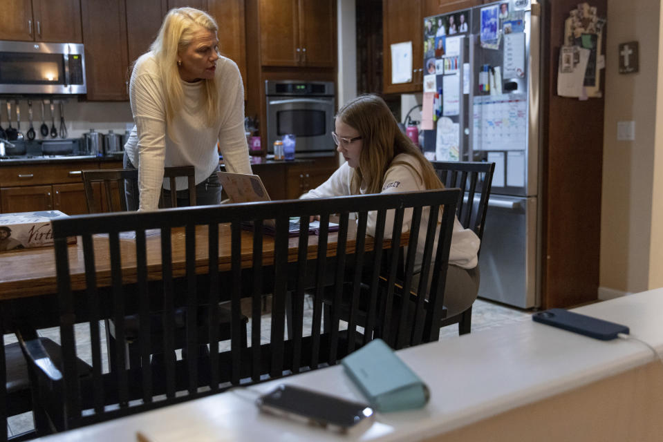 Cell phones charge on a ledge between the living room and kitchen as Steph Bulkeley helps Kate select school courses, Friday, Feb. 16, 2024, in Westport, Conn. With the damaging consequences of social media increasingly well documented, many parents are trying to raise their children with restrictions or blanket bans. Teenagers themselves are aware that too much social media is bad for them, and some are initiating social media “cleanses” because of the toll it takes on mental health and grades. (AP Photo/Julia Nikhinson)