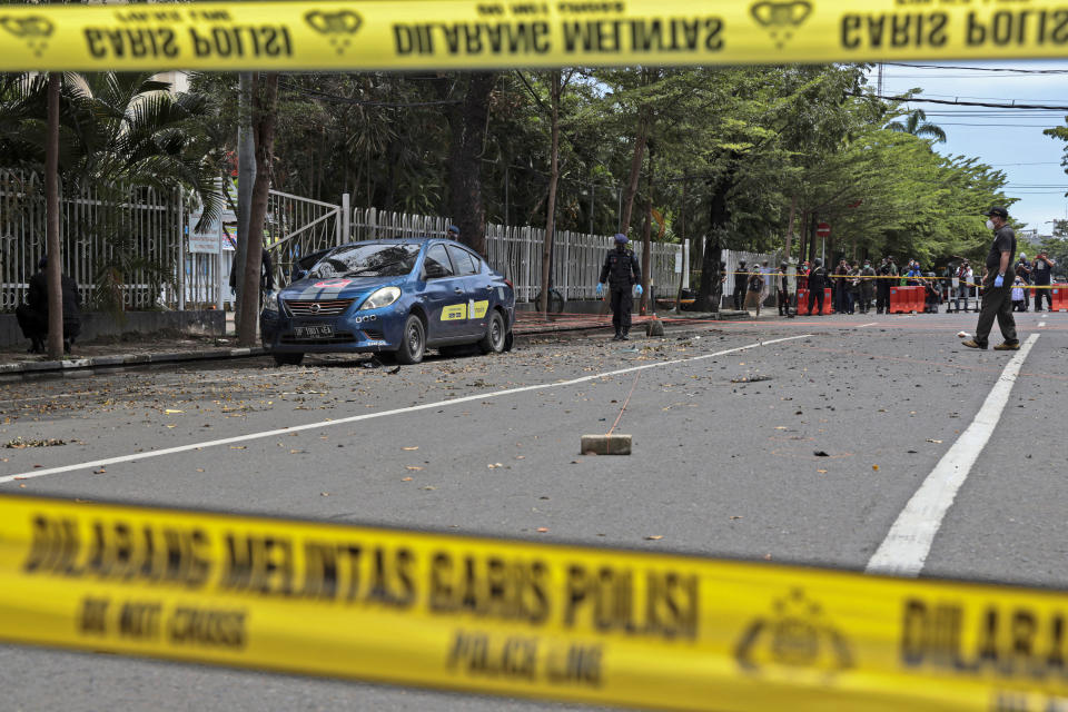 Members of the police bomb squad inspect the area around the site of Sunday's suicide bomb attack at the Sacred Heart of Jesus Cathedral in Makassar, South Sulawesi, Indonesia, Monday, March 29, 2021. Two attackers believed to be members of a militant network that pledged allegiance to the Islamic State group blew themselves up outside the packed Roman Catholic cathedral during a Palm Sunday Mass on Indonesia's Sulawesi island, wounding a number of people, police said. (AP Photo/Yusuf Wahil)