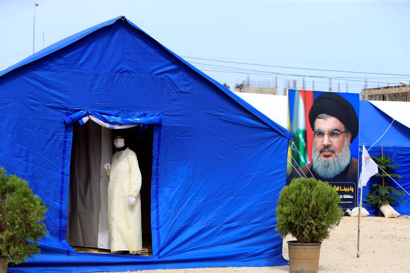 A medic wearing protective gear stands inside a tent facility in al-Ghaziyeh