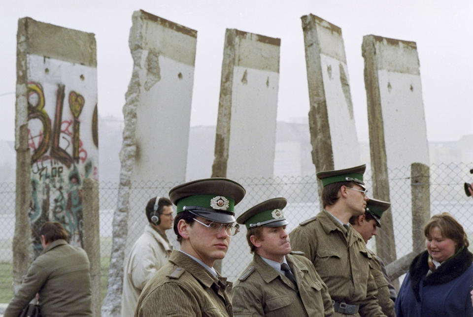 FILE - In this Nov. 13, 1989, file photo, East German border guards stand in front of segments of the Berlin Wall, which were removed to open the wall at Potsdamer Platz passage in Berlin. Months before the Berlin Wall fell on Nov. 9, 1989, with the Soviet stranglehold over the Eastern Bloc crumbling, a young political scientist named Francis Fukuyama made a declaration that quickly became famous. It was, he declared, “the end of history.” (AP Photo/John Gaps III, File)