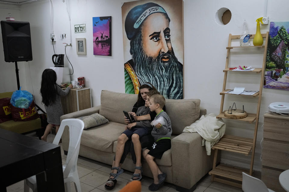 An Israeli family sit in a bomb shelter of an apartment building to stay safe from rockets fired from Gaza Strip toward Israel, in the southern Israeli city of Ashdod, Saturday, May 13, 2023. It was the fifth day of fighting between Israel and Islamic Jihad, the second-largest militant group in Gaza. (AP Photo/Ohad Zwigenberg)