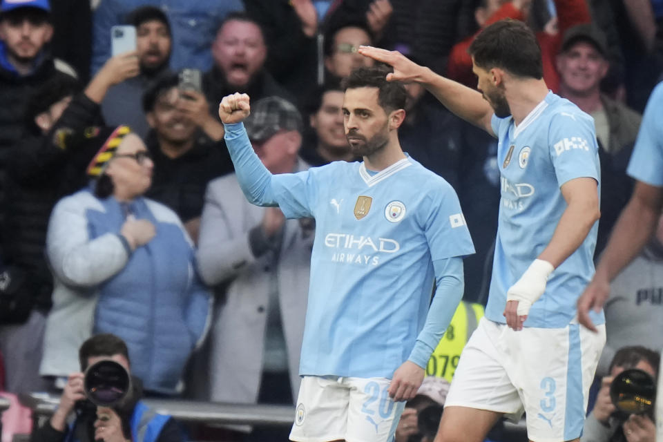 Manchester City's Bernardo Silva, left, celebrates with teammates after scoring the opening goal during the English FA Cup semifinal soccer match between Manchester City and Chelsea at Wembley stadium in London, Saturday, April 20, 2024. (AP Photo/Alastair Grant)