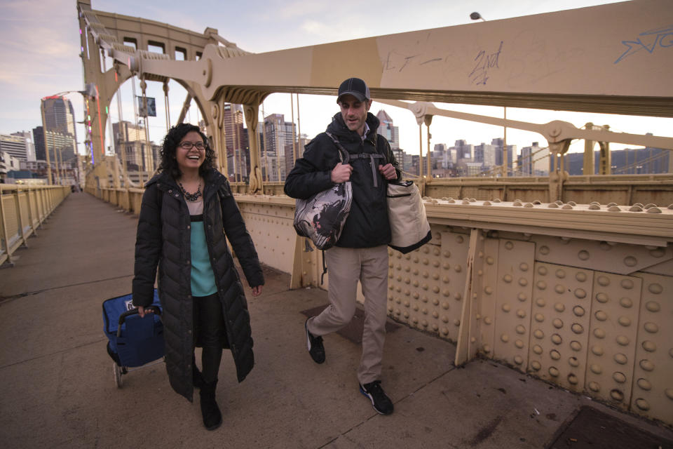 This image released by 412 Food Rescue shows Melinda Angeles and Eli Thomas transporting a donation of bagels from Bruegger's Bagels across the 9th Street bridge to a North Side senior center in Pittsburgh. While millions of people struggle with food insecurity and hunger nationwide, the USDA estimates that more than 30% of the food in America is wasted each year. (Nancy Andrews/412 Food Rescue via AP)