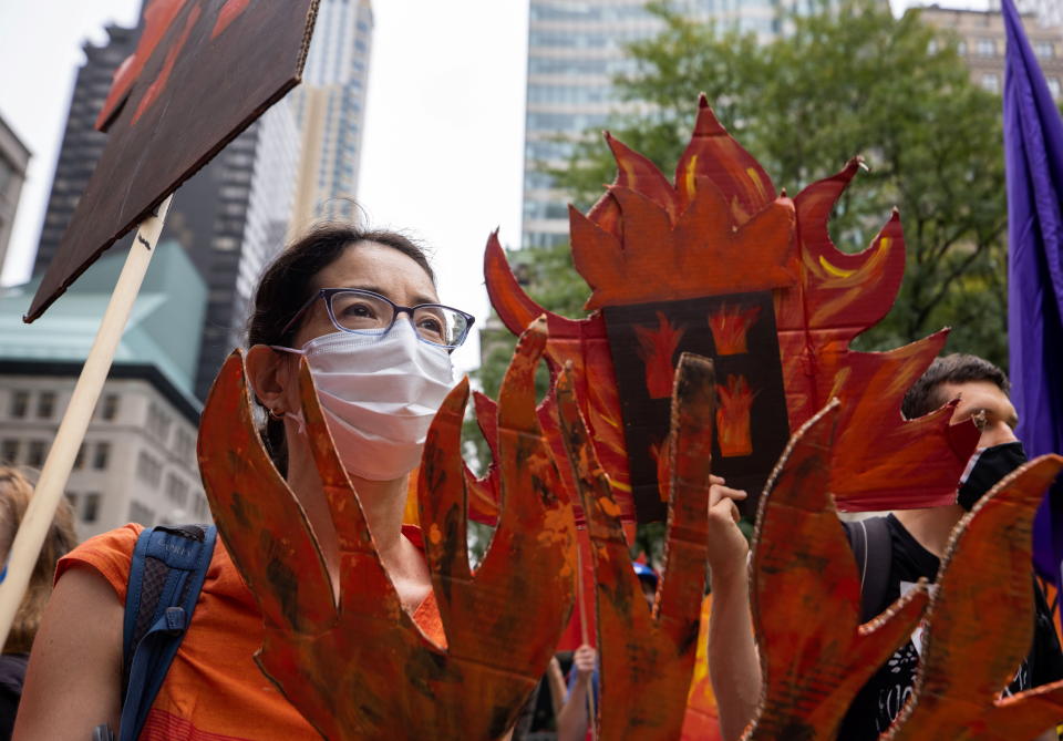 People hold cardboard signs cut in shapes of burning trees and homes and flames, symbolizing the present day impacts of climate change, during a &#39;non-violent resistance&#39; climate change protest organized by Extinction Rebellion in the Manhattan borough of New York City, U.S., September 17, 2021. REUTERS/Caitlin Ochs