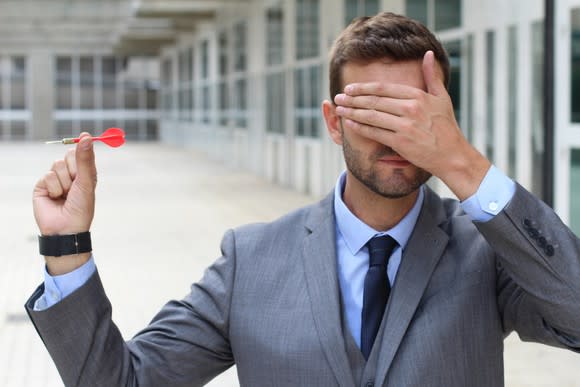 Man throws dart with his eyes covered.