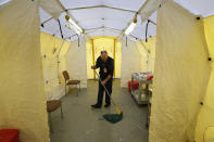 Steve Moody, director of nursing at Central Maine Medical Center, mops the floor of a tent outside the emergency entrance to the hospital where patients are tested for of the coronavirus Friday, March 13, 2020, in Lewiston, Maine. U.S. hospitals are setting up circus-like triage tents, calling doctors out of retirement, guarding their supplies of face masks and making plans to cancel elective surgery as they brace for an expected onslaught of coronavirus patients. (AP Photo/Robert F. Bukaty)