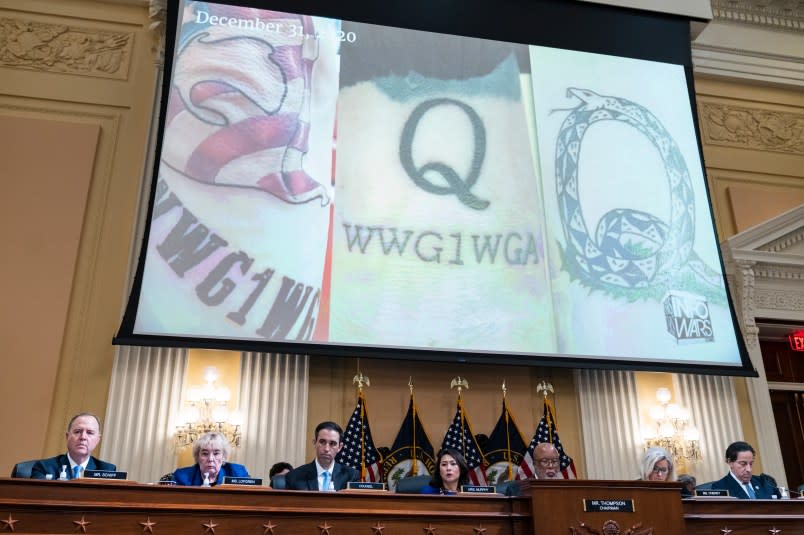 UNITED STATES – JULY 12: QAnon imagery appears on a screen during the Select Committee to Investigate the January 6th Attack on the United States Capitol hearing to present previously unseen material and hear witness testimony in Cannon Building, on Tuesday, July 12, 2022. Appearing from left are, Rep. Adam Schiff, D-Calif., Rep. Zoe Lofgren, D-Calif., counsel, Rep. Stephanie Murphy, D-Fla., Chairman Bennie Thompson, D-Miss., vice chair Rep. Liz Cheney, R-Wyo., and Rep. Jamie Raskin, D-Md. (Tom Williams/CQ-Roll Call, Inc via Getty Images)