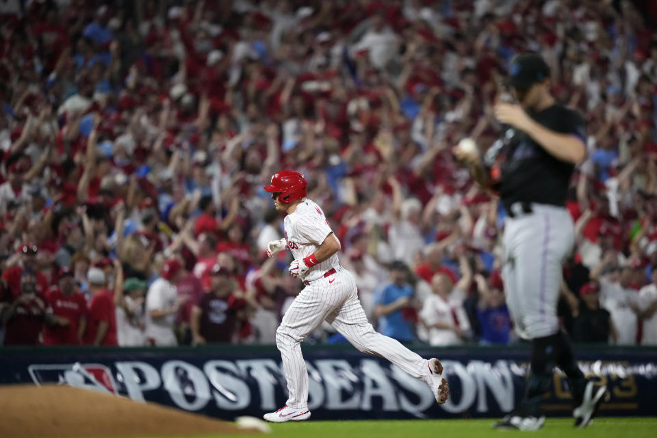 Philadelphia Phillies' J.T. Realmuto, left, rounds the bases after hitting a home run against Miami Marlins pitcher David Robertson during the fourth inning of Game 2 in an NL wild-card baseball playoff series, Wednesday, Oct. 4, 2023, in Philadelphia. (AP Photo/Matt Slocum)