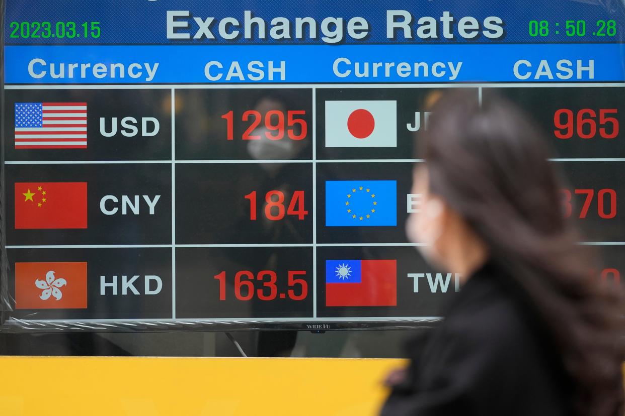 FILE-A woman wearing a face mask looks at an electronic foreign currency exchange rates in downtown Seoul, South Korea (Copyright 2023 The Associated Press. All rights reserved)
