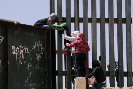 Migrants jump over the border wall to cross the U.S. from Mexico, in Ciudad Juarez