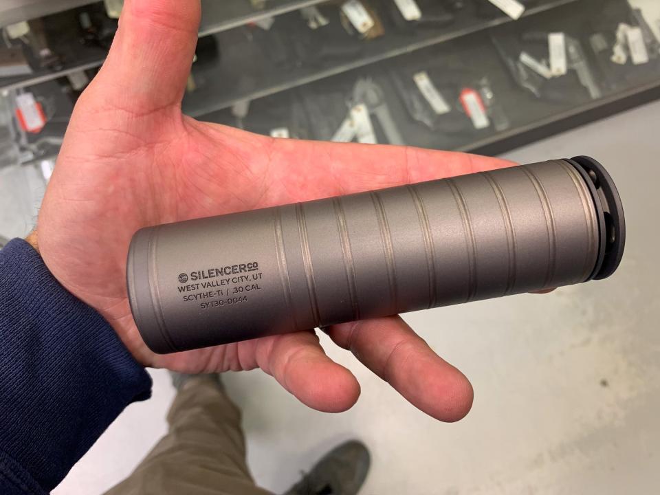 A SilencerCo suppressor in hand.